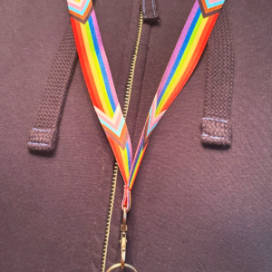 Rainbow lanyard with progressive pride stripes against a zipped hoodie, representing York Pride's inclusive community spirit.