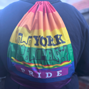 Rainbow drawstring bag with York Pride castle design worn by a person.